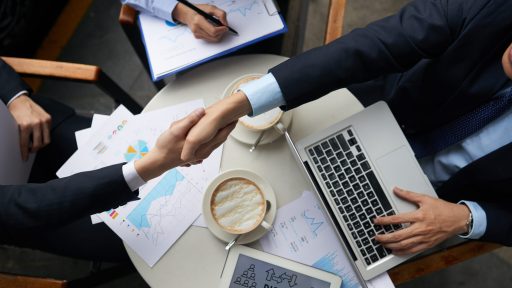 Business people shaking hands overtable with documents